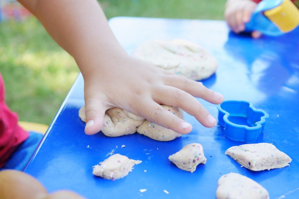 photo of child s hand playing clay