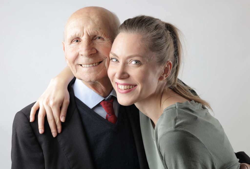 delighted senior father and adult daughter hugging in studio